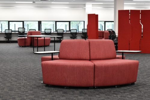 Red modular couches and study cubicles in a bright, carpeted space.