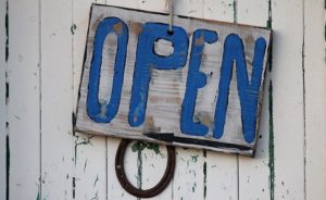 A sign with the word ‘open’ on it hanging from a wooden wall