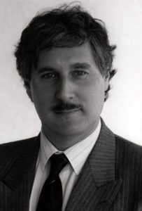 A black and white photograph of Professor Charles Sampford looking straight to camera